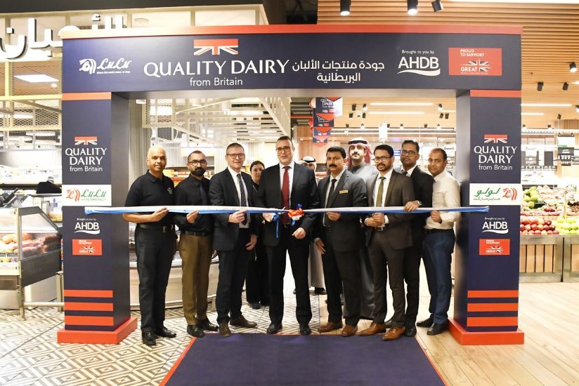 A group of men standing underneath a Quality Dairy from Britain sign in Lulu Hypermarket.